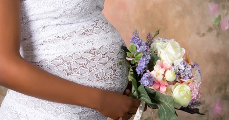 Closeup of a pregnant belly in wedding dress